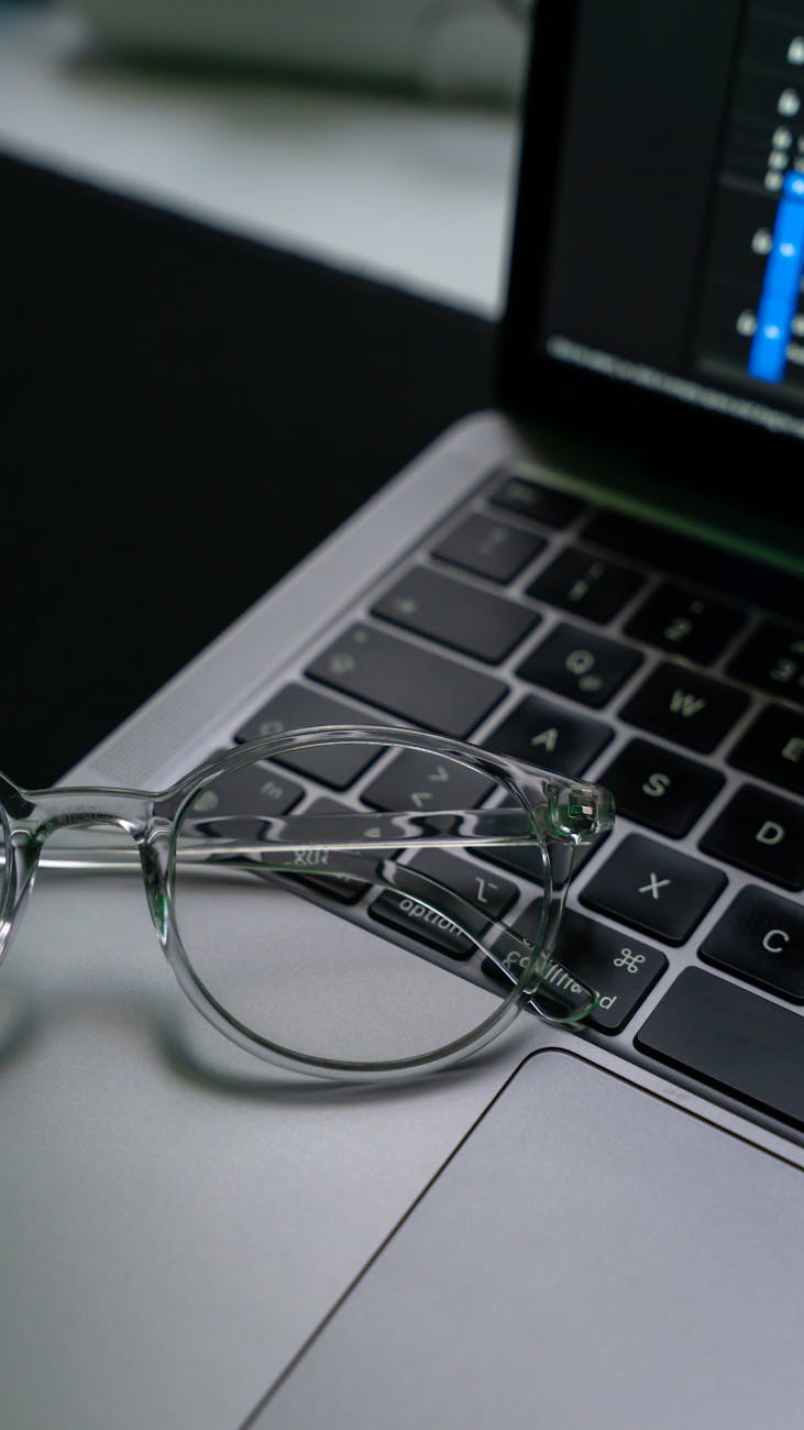 Close-up view of eyeglasses on laptop keyboard, reflecting a digital workspace scene.
