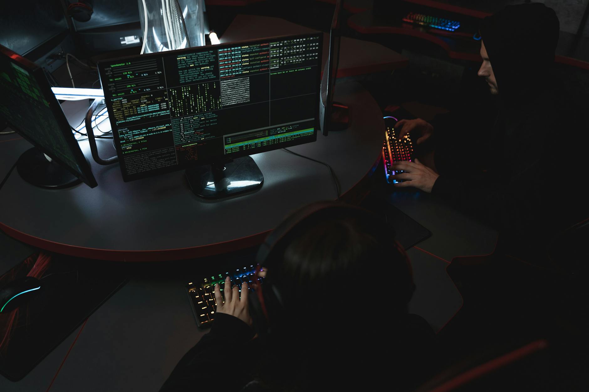 A group of people in a dark room working on computers, related to cybersecurity.
