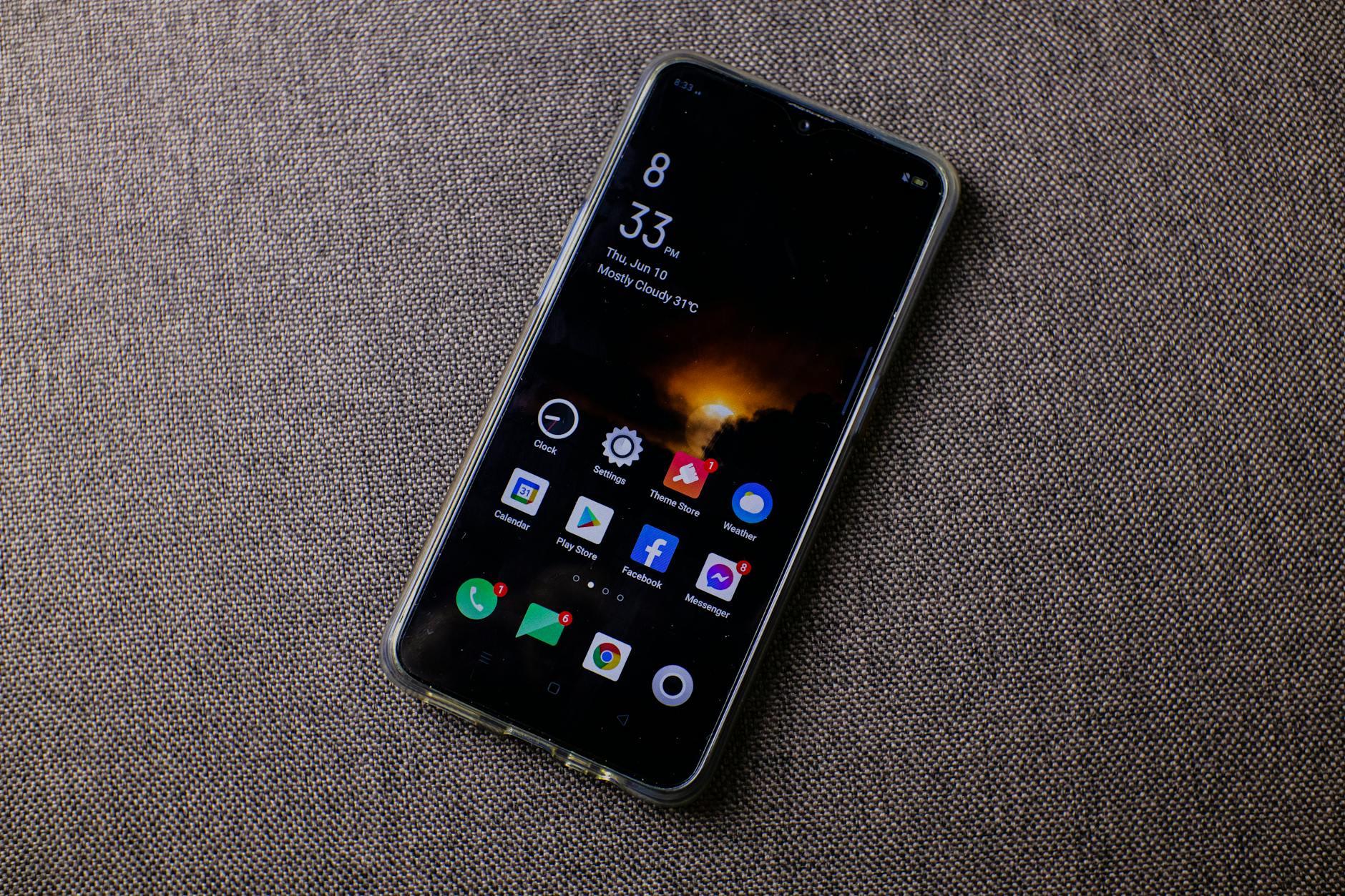 Close-up of a smartphone displaying apps on a textured surface, showcasing modern technology.