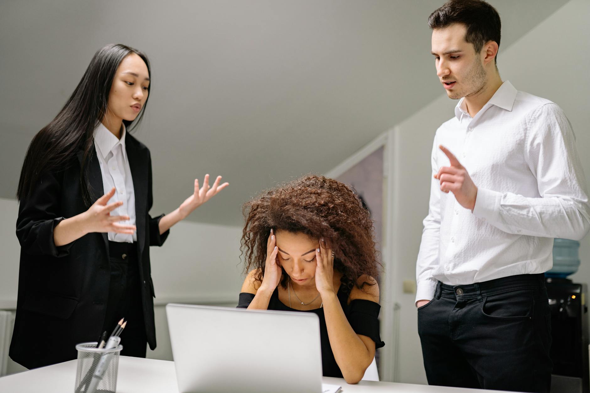 Diverse coworkers in an office dealing with a stressful work situation around a laptop.