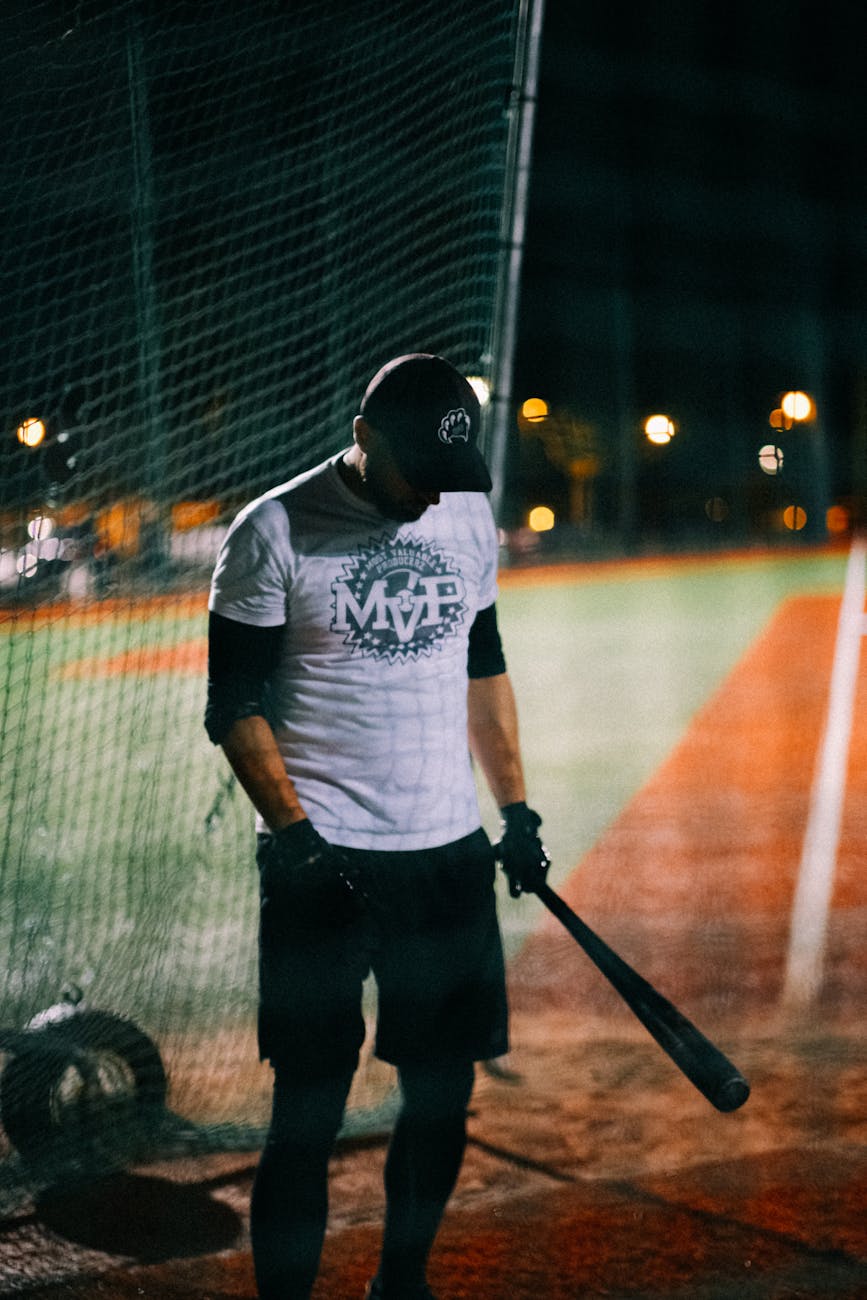 A baseball player holding a bat at night in an illuminated stadium.