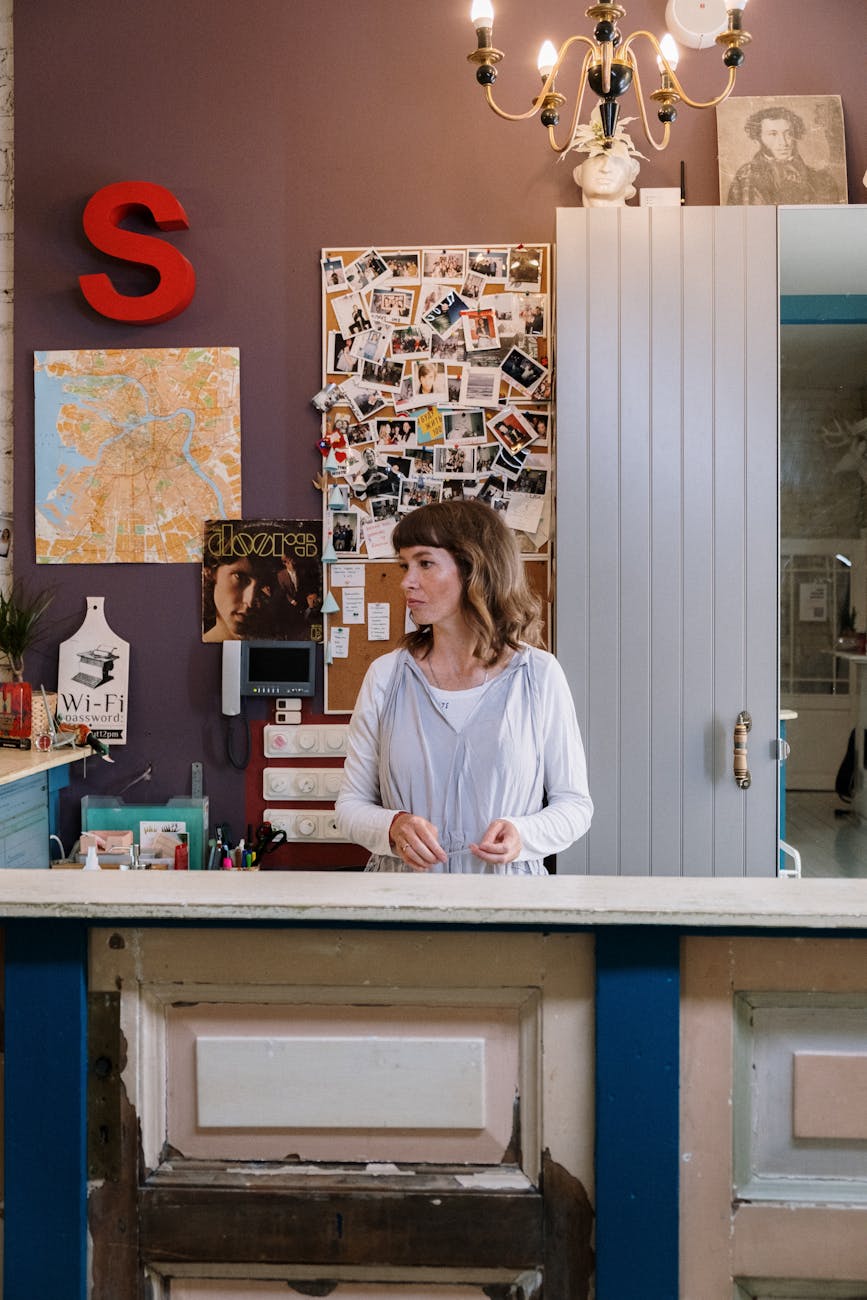 Receptionist standing behind a welcoming hotel front desk with decor and bulletin board.