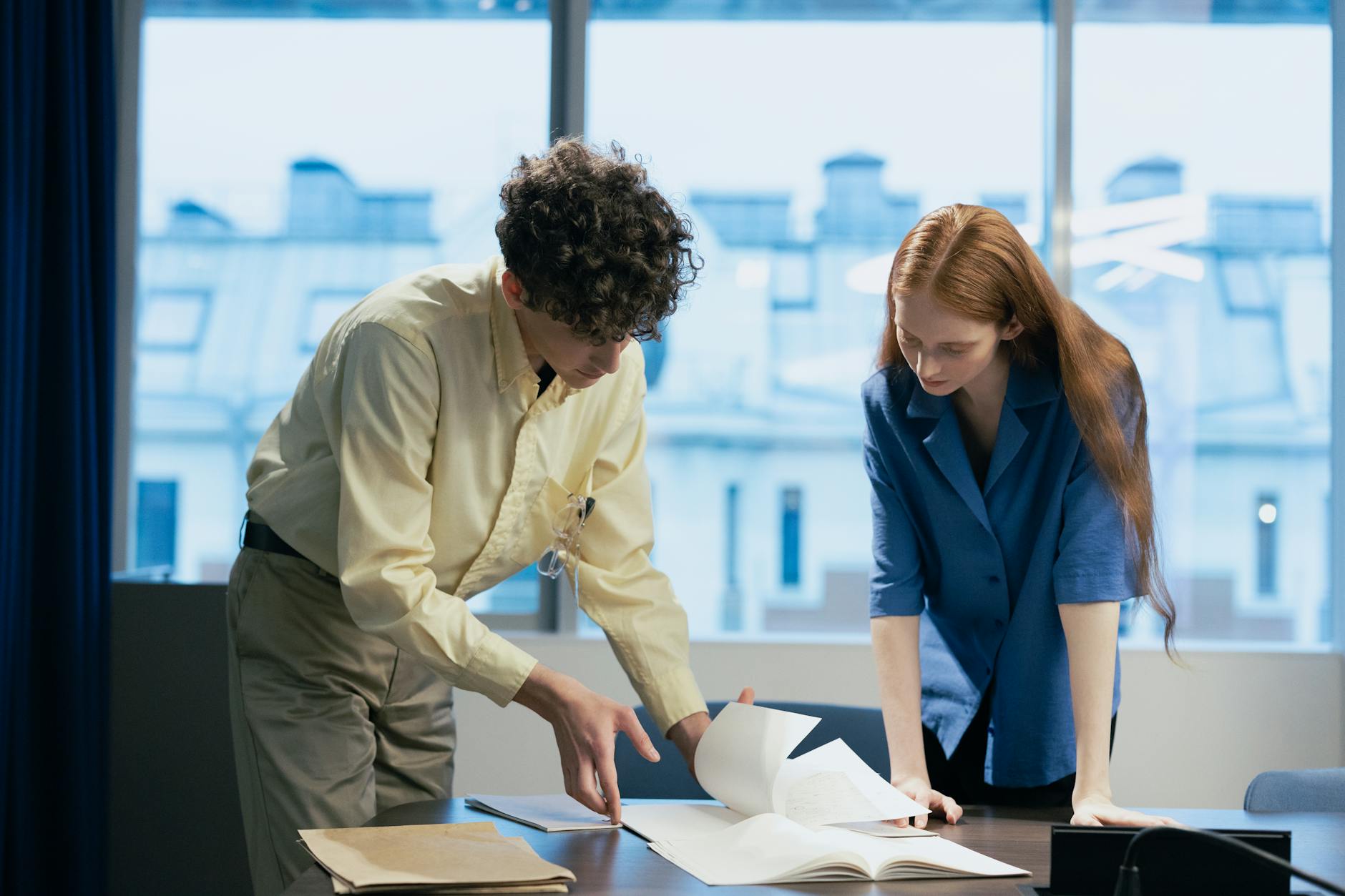 Two colleagues reviewing documents in a modern office setting.