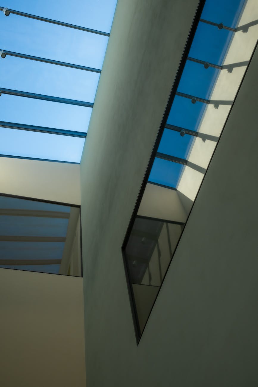 Low angle view of a modern building interior featuring a glass ceiling and geometric architectural design.