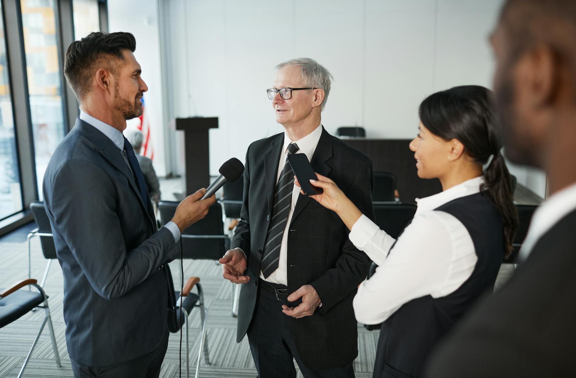 Journalists conduct an interview with a senior executive in a formal office setting.