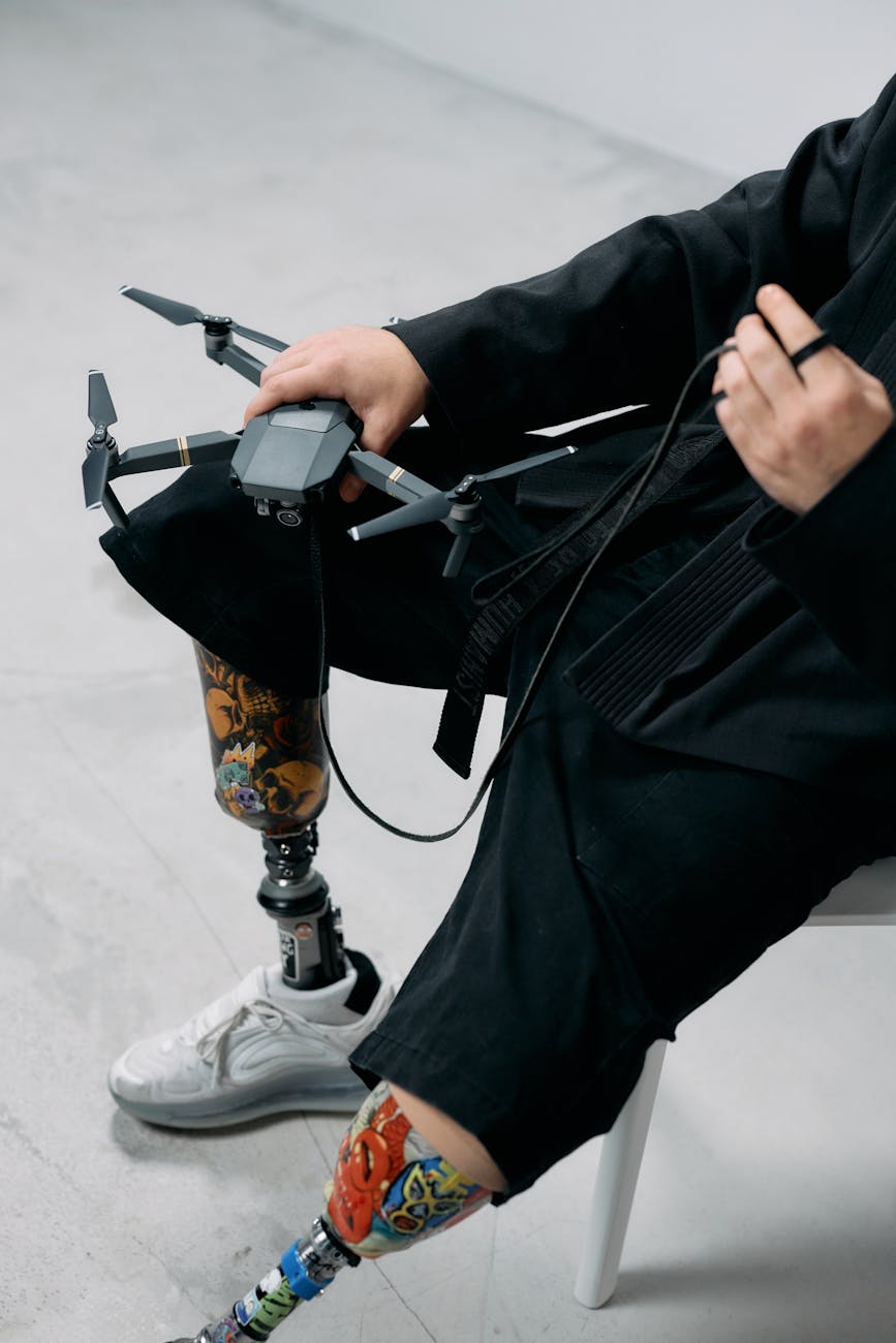 Close-up of a person using a prosthetic leg while holding a drone, showcasing modern technology integration.