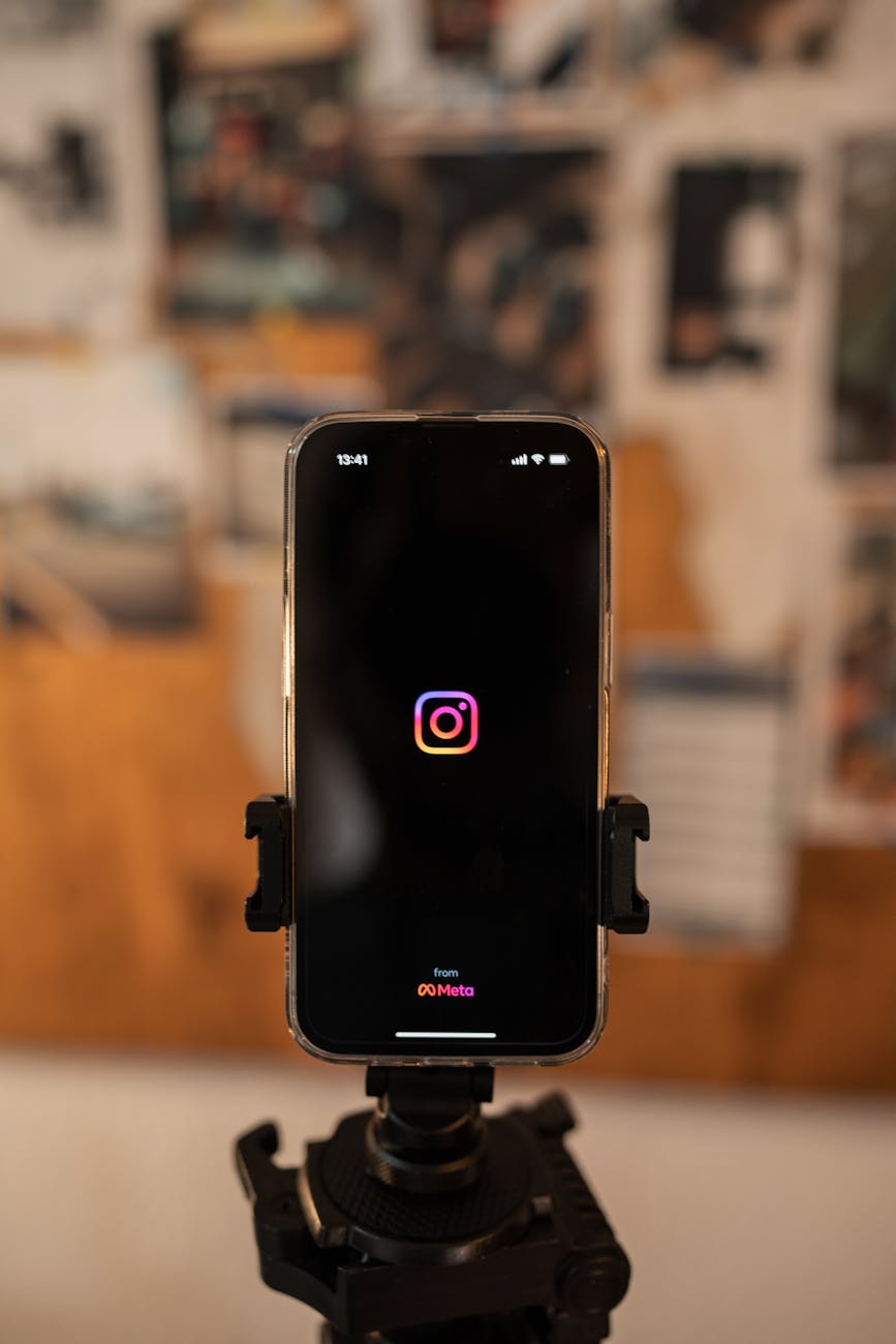 Smartphone displaying Instagram logo on tripod, perfect for social media concepts.