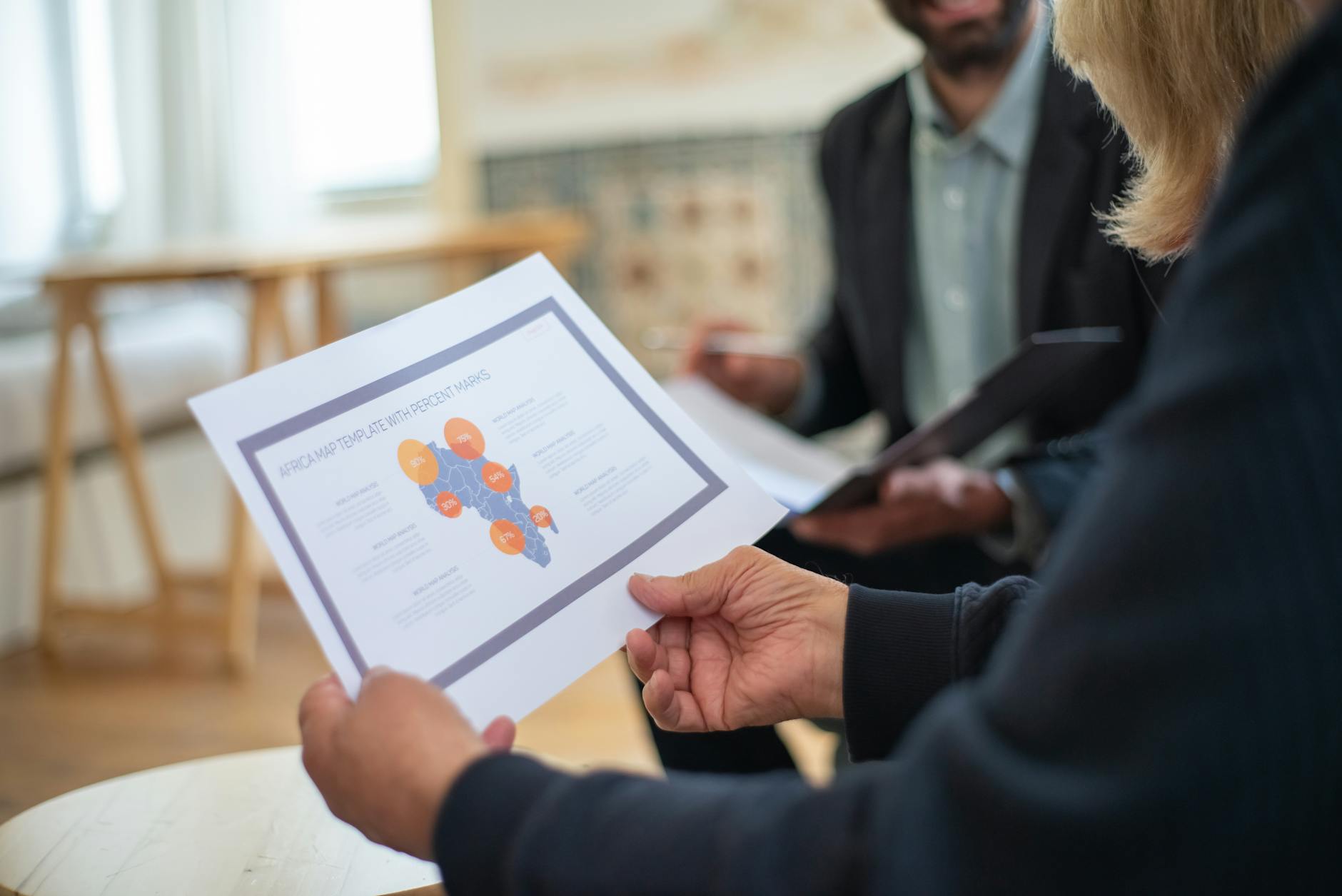 Three professionals discussing a data presentation in an office setting.