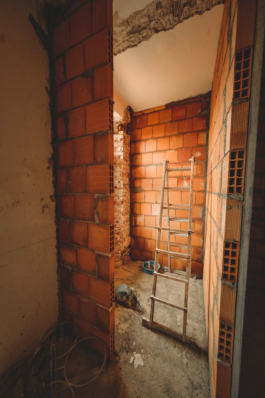 A construction site with a ladder leaning against red brick walls, showcasing renovation activities.