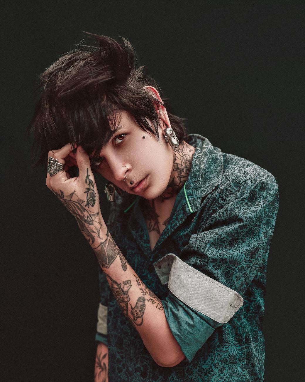 Portrait of a stylish tattooed model with a punk-inspired hairstyle in a studio setting.