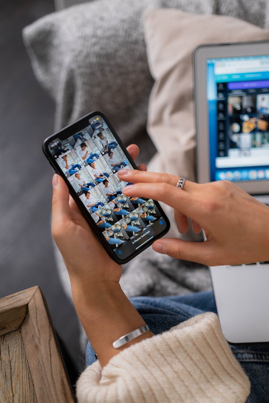 High angle shot of a person editing photos on a smartphone and laptop indoors.
