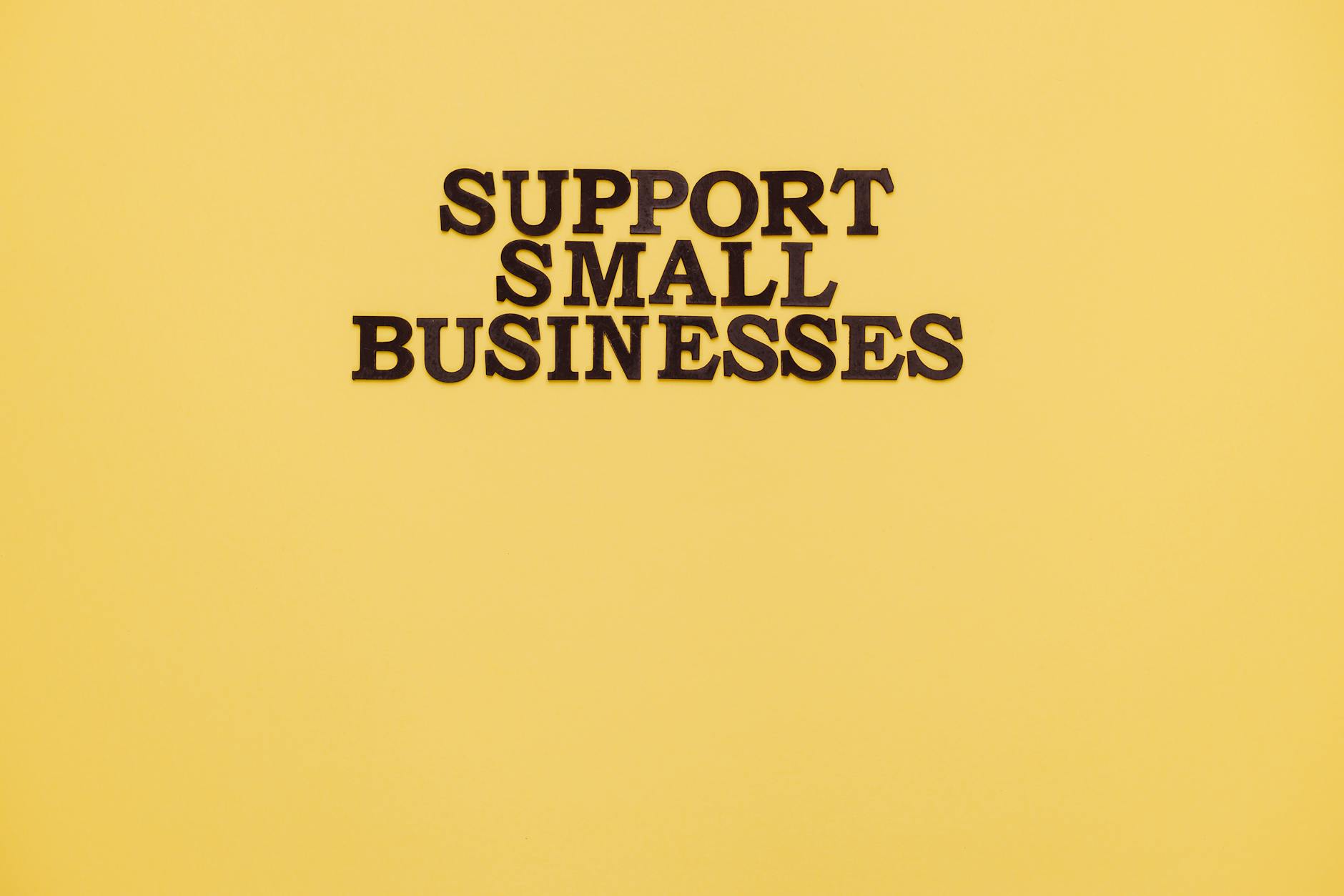 Inspirational image with 'Support Small Businesses' text on a warm yellow background.