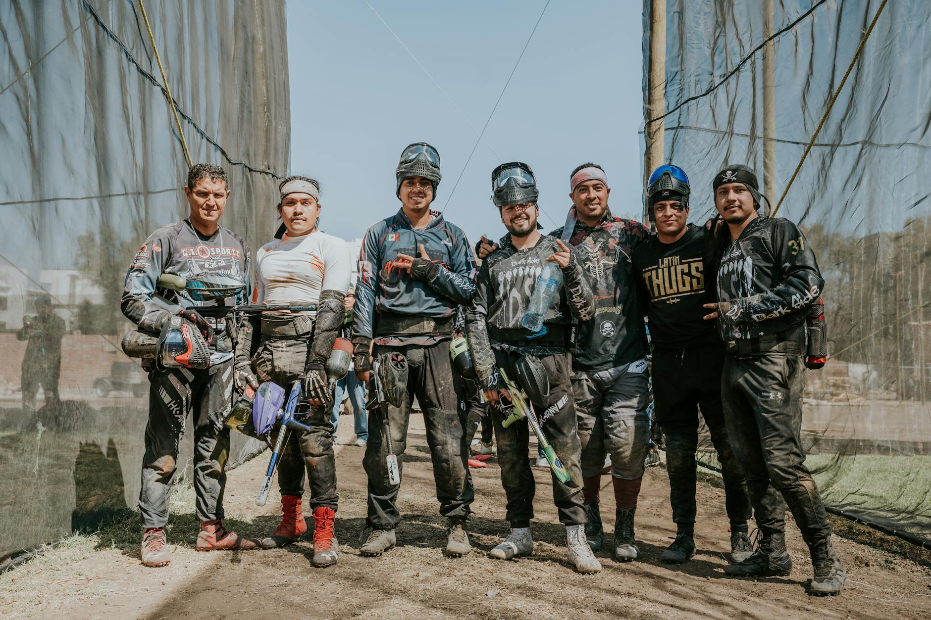 A group of men enjoying an outdoor paintball game in gear, smiling for the camera.