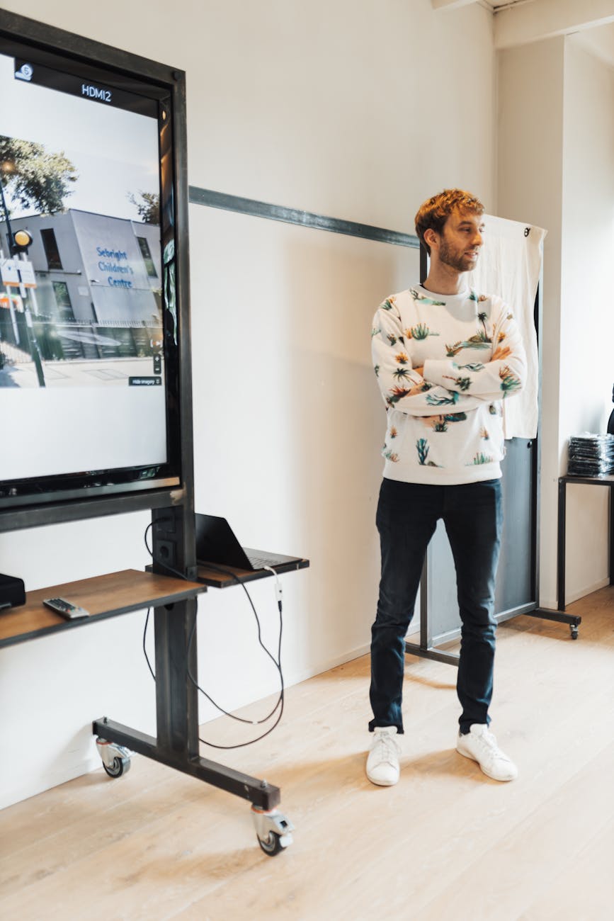 Young man giving a presentation in a modern office with digital display.