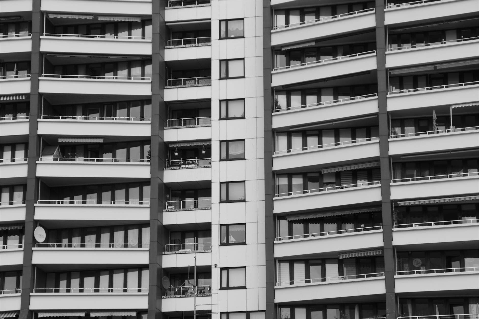 Stylish modern apartment building showcasing contemporary architecture with multiple balconies in grayscale.