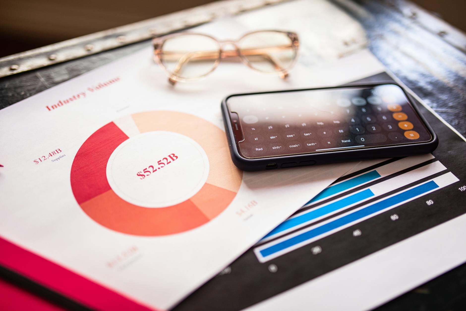 Smartphone on business documents with charts and graphs, illustrating financial analysis.