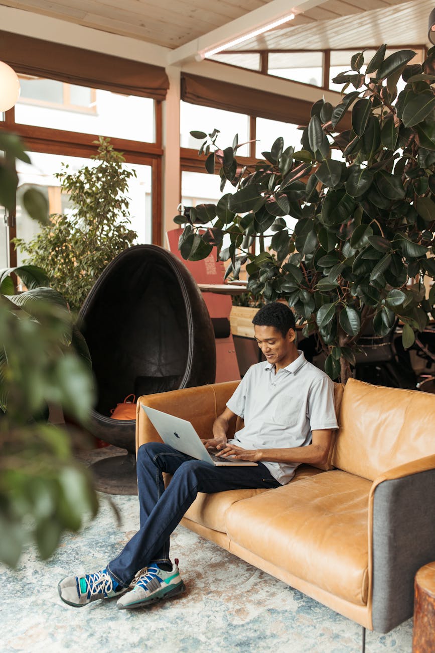 Man using laptop in a modern creative workspace surrounded by indoor plants.
