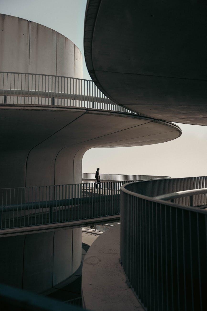 Silhouette of a person walking on a modern, curved architectural structure.