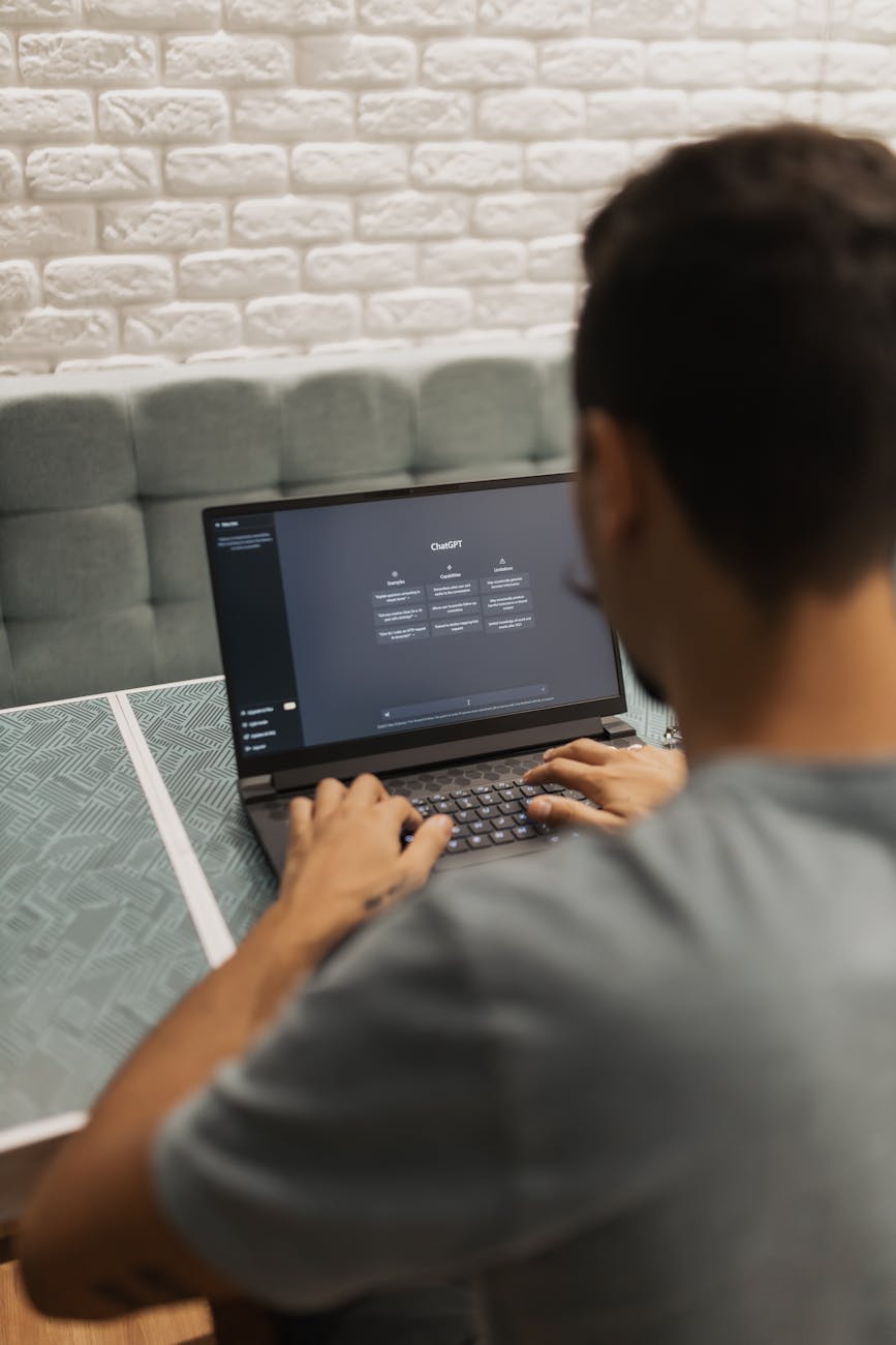 A man interacts with a laptop displaying the ChatGPT system indoors, focusing on technology.