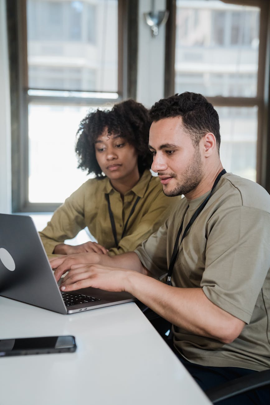 Two colleagues working collaboratively on a laptop in an office.