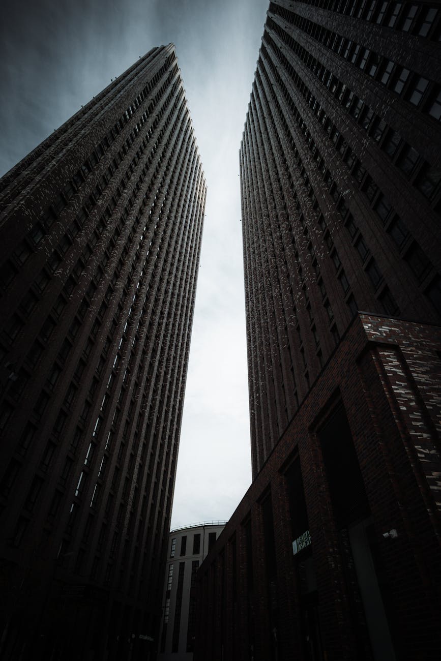 A low-angle view of two towering skyscrapers against a dramatic sky, showcasing modern urban architecture.
