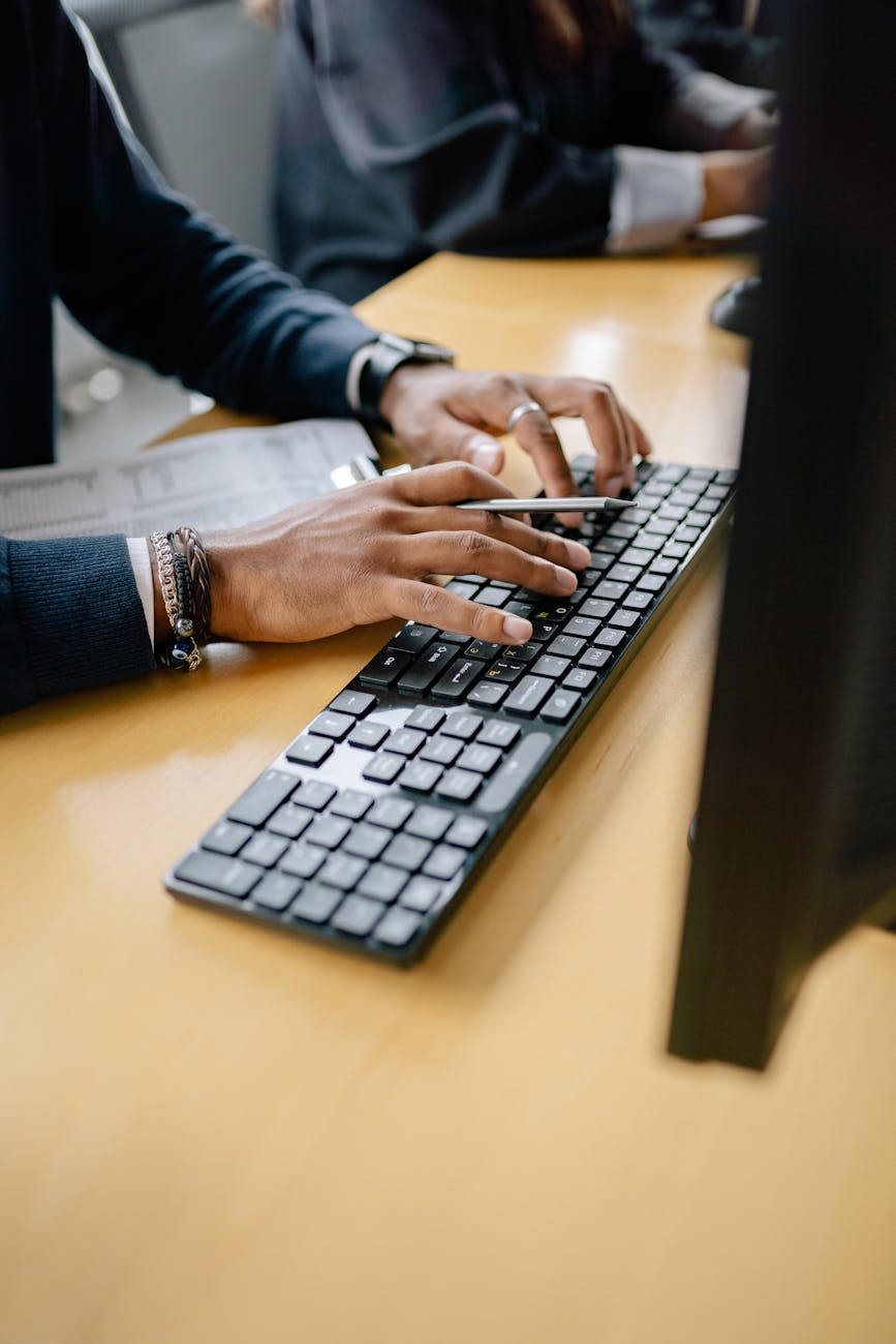 Close-up of hands typing on keyboard in an office setting, showcasing work professionalism.