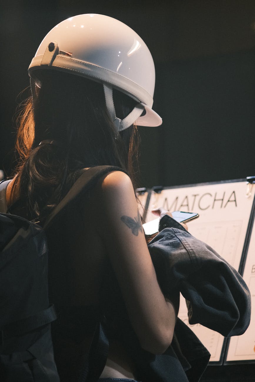 A woman wearing a helmet checks her phone inside a cafe.